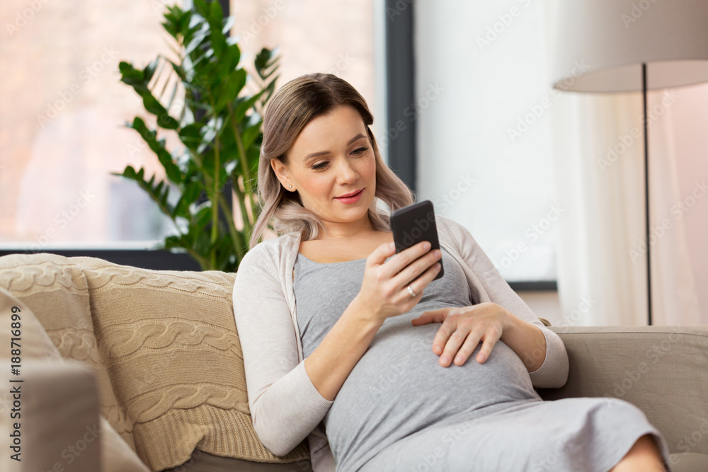 Wall mural happy pregnant woman with smartphone at home