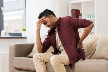 unhappy man suffering from backache at home
