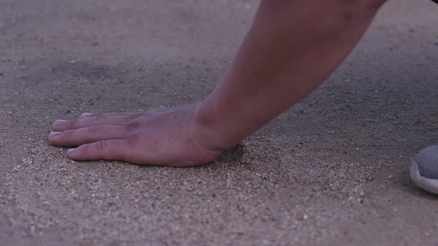 Close up of man's hand touching sand at the shore of the sea - concept of native place. man holds his hand over the sand on the beach - concept of vacations and tourism. Sand on the hand at green sand
