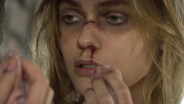 A beautiful girl wipes a napkin with blood from her lips