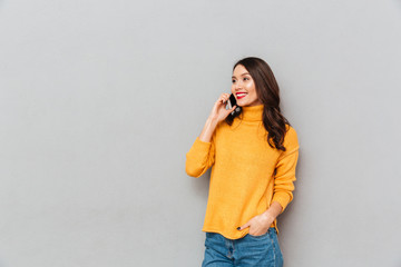 Woman in sweater with arm in pocket talking by smartphone