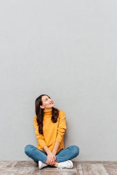 Vertical image of Smiling brunette woman sitting on the floor