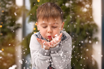 the boy blows the snow from his hands - obrazy, fototapety, plakaty