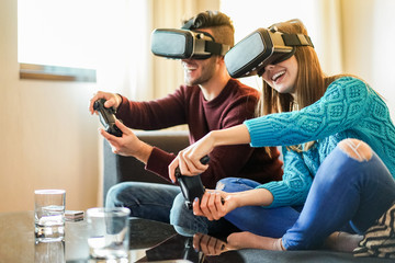 Happy friends playing video games wearing virtual reality glasses in their apartament 