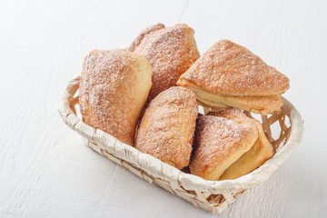 Homemade cookies in a basket on white wooden background.