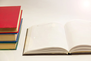 The opened book lies next to a stack of closed books on a gray background.