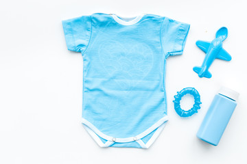 Blue baby clothes for little boy. Bodysuit, toys, cosmetics on white background top view copy space