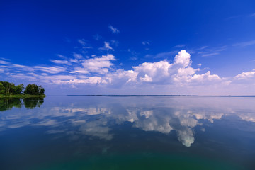 clean blue sky reflected in calm water on summer day