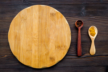 Cook a meal. Mock up for menu or recipe. Wooden cutting board near ingredients on dark wooden background top view