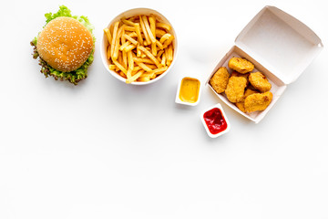 Fast food. Chiken nuggets, burgers and french fries on white background top view space for text - obrazy, fototapety, plakaty