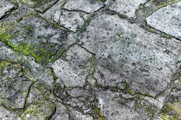 Texture of vintage stone footpath. Texture of aged rock with green moss.