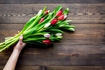 First spring flowers. Bouquet of colorful tulips on dark wooden background top view copy space