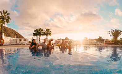Happy friends drinking champagne in pool party at sunset - obrazy, fototapety, plakaty