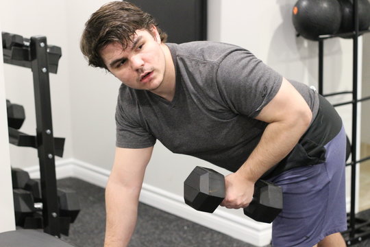 Young male exercising in a small weight room 