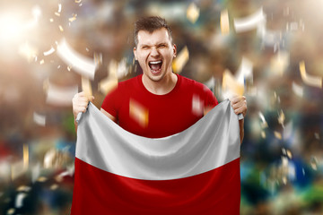 Fototapeta Polish fan, a fan of a man holding the national flag of Poland in his hands. Soccer fan in the stadium. Mixed media obraz