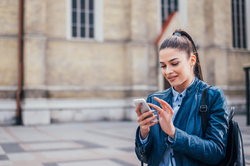 Beautiful brunette girl using smartphone outdoor.