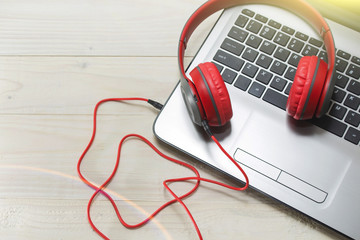 Obraz premium the laptop and red wooden headphones on a light background.