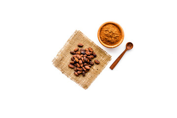 Main ingredient for chocolate. Cocoa powder in bowl near cocoa beans on white background top view copy space