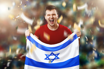 Fototapeta premium An Israeli fan, a fan of a man holding the national flag of Israel in his hands. Soccer fan in the stadium. Mixed media