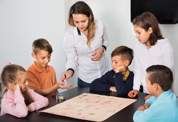 Boys and little girls playing at board game
