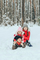 Fototapeta na wymiar joyful children playing with their mother in the winter forest lying on the snow