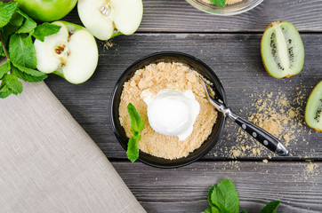 Top view close up Apple crumble dessert with vanilla ice cream, green mint, kiwi on grey wooden...