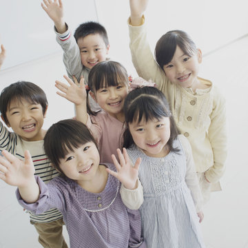 Portrait of group of smiling children with raised hands