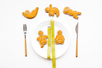 Sport and healthy diet for slimming. Plate, measuring tape and cookies in shape of yoga asans on white background top view copy space