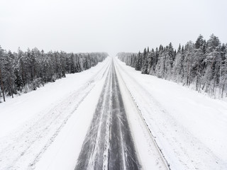 Obraz premium Empty lane of northern asphalt highway at winter blizzard. Northern Karelia, Russia