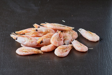 Delicious boiled shrimps with lemon and greens on a black background