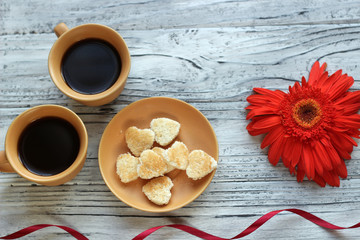 On a wooden background there is a flower in the form of a heart next to a note with wishes for Valentine's Day. The concept of Valentine's Day.