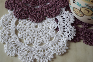 White and purple hand hooked coaster. Knitted holders for hot work