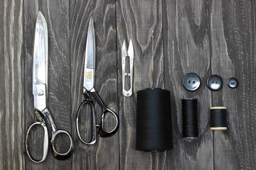 On a black wooden stench, close-up, scissors spool of thread with a needle.