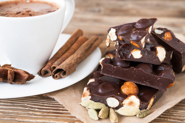 Coffee break with cinnamon and anise stars, cardamom on a rustic table and dark chocolate with hazelnuts