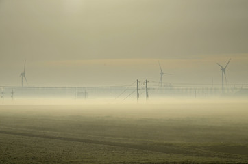 Nebel &uuml;ber einem Feld mit Hochspannungsmasten und Windkraftr&auml;dern in Holland, Niederland