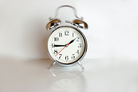 White retro clock isolated against a white background casting a reflection