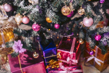 New Year's tree decorated with toys with gift boxes under it.