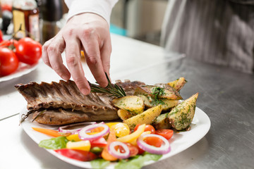 the chef prepares in the restaurant. Grilled rack of lamb with fried potatoes and fresh vegetables. closeup