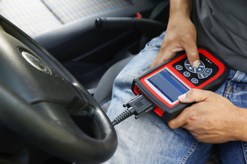 A mechanic inspecting a car using an electronic device. Computer are used due to cars increasing electronic complexity