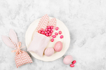 Easter holiday composition with eggs, bunny bag with candy on the plate and heart