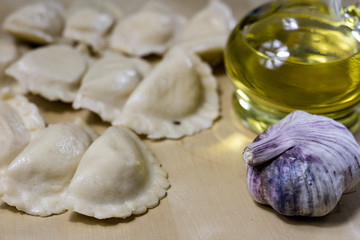 Fototapeta na wymiar Tasty dumplings arranged on a light wooden kitchen table. Dumplings bowl and oil in the kitchen.