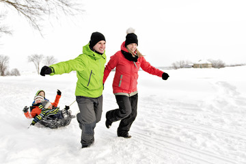 Fototapeta na wymiar Family Pulling Sledge Through Snowy Landscape