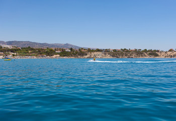 Залив Средиземного моря и плывущий водный мотоцикл (скутер) на нем, виден берег и волны