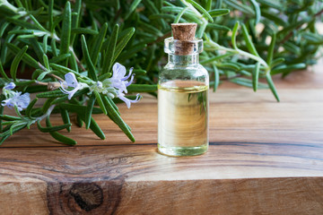 A bottle of rosemary essential oil with fresh blooming rosemary twigs