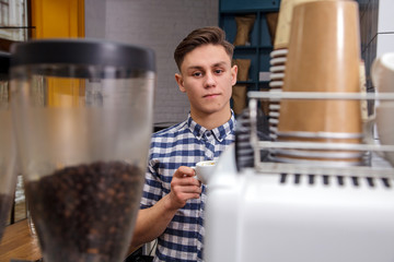 Young handsome barista hipster making coffee cafe man machine grains hot steam milk shirt espresso latte cappuccino drink