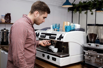 Young handsome barista hipster making coffee cafe man machine grains hot steam milk shirt cage espresso latte cappuccino