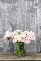 Vase with beautiful bouquet of ranunculus flowers on wooden table. rustic background with copy space. Close up Persian buttercup flower.