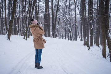 Fototapeta na wymiar Young woman tourist takes photos of nature in winter
