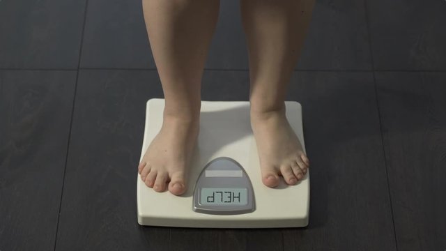 Girl stepping on scales, word help written on screen, health problems, dieting