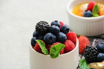 Mixed fresh Berries in a white bowl with Creme Brulee on the side